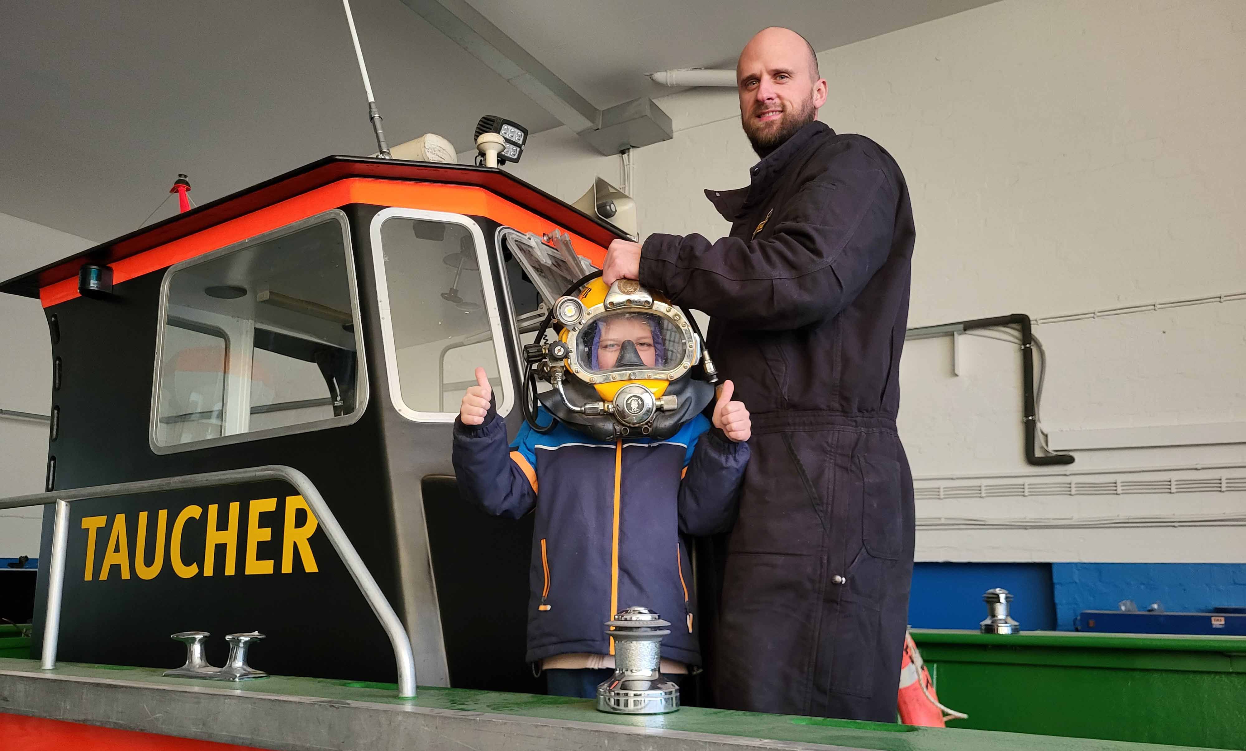 Kind mit Tauchhelm hat beide Daumen hoch